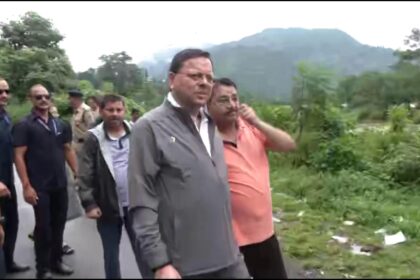 Uttarakhand CM Pushkar Singh Dhami inspecting flood-affected areas in Kesarwala, Dehradun after heavy rainfall, with damaged roads, submerged temple, and affected houses in the background