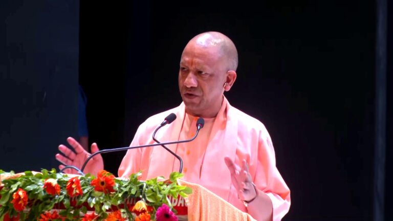 Uttar Pradesh Chief Minister Yogi Adityanath lighting a ceremonial lamp at the 'Deepotsav Se Rashtrotsav' program in Gorakhpur, surrounded by devotees and RSS members.