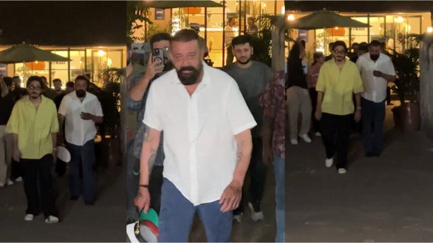 Sanjay Dutt walking in Mumbai wearing a white shirt and denim, casual confident look with night street ambience.