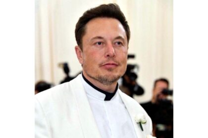 Elon Musk smiling during a business event as his net worth rises close to 750 billion dollars due to Tesla and SpaceX growth