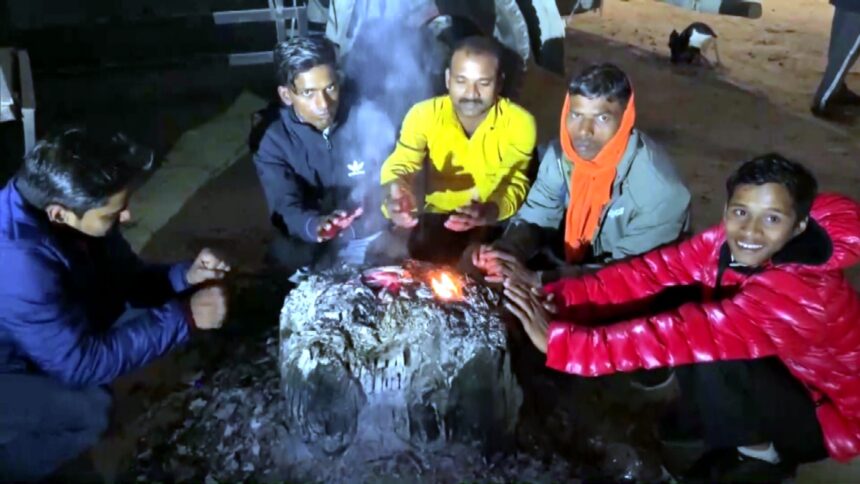 अयोध्या में ठंड से बचने के लिए अलाव के पास गर्माहट लेते हुए लोग।