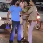 Mathura Firing Incident: Police personnel detaining a man carrying a licensed revolver after a firing incident in Mathura's Krishna Nagar area while a crowd gathers on the road.