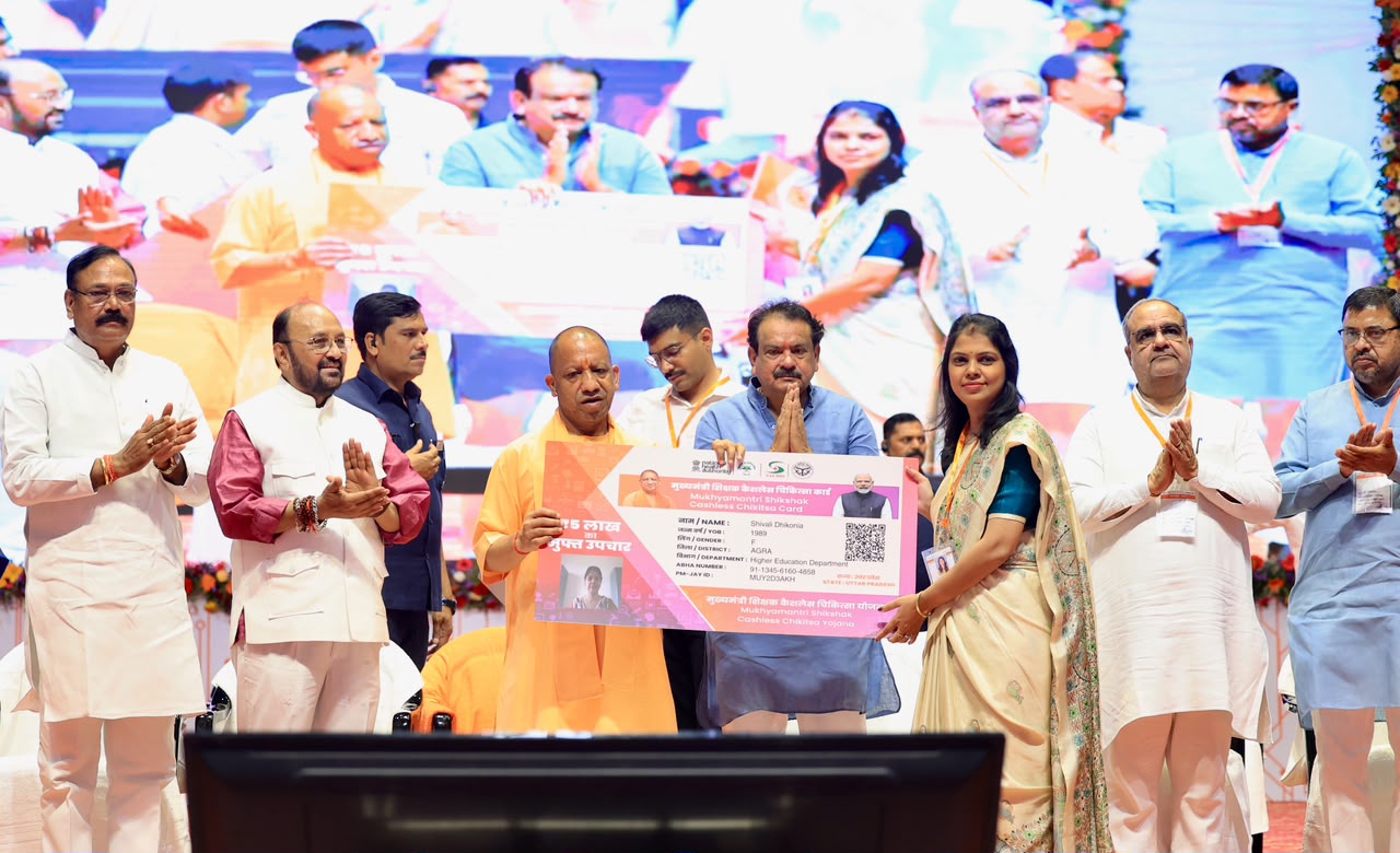 UP CM Yogi Adityanath launching the Teacher Cashless Medical Scheme at an event in Agra with education officials and beneficiaries.
